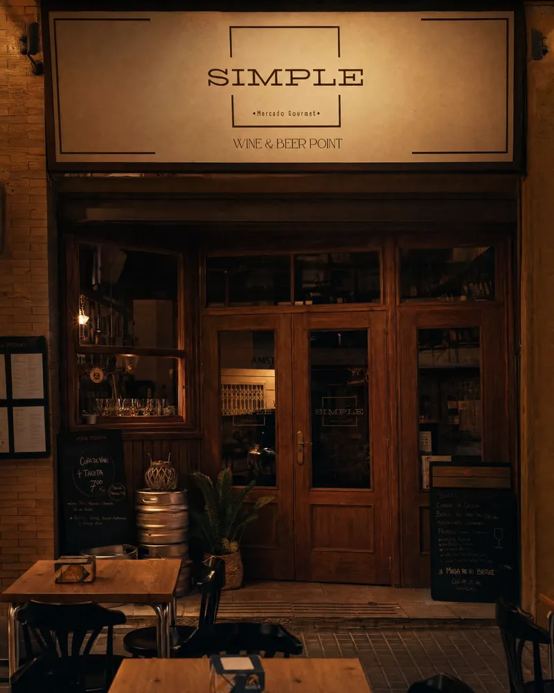 La fachada de Simple: el letrero «Simple, Mercado Gourmet, Wine & Beer Point» sobre las puertas de madera, con pizarras y mesas en la acera.